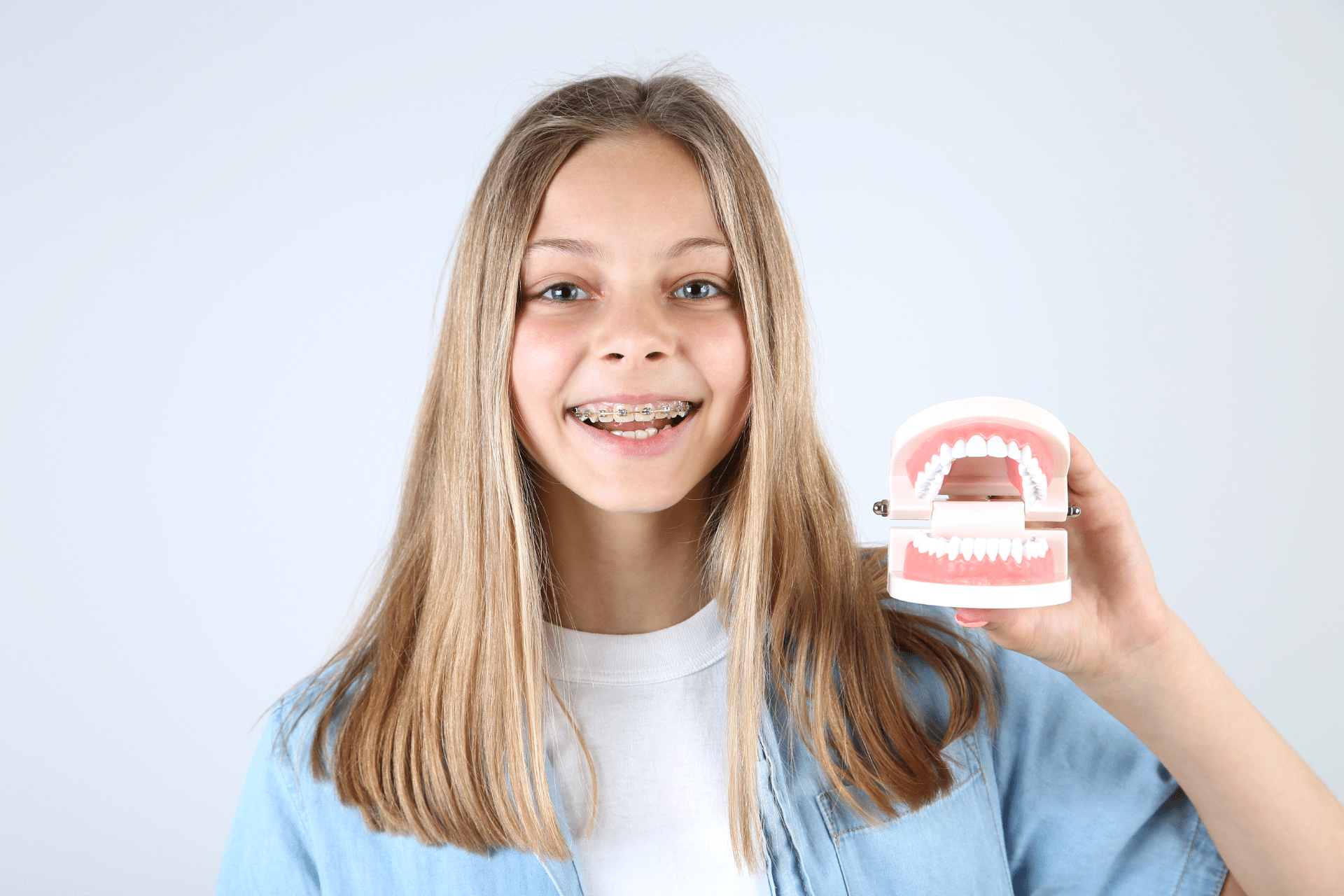 Child with braces holding a dental model in Sugar Land, TX