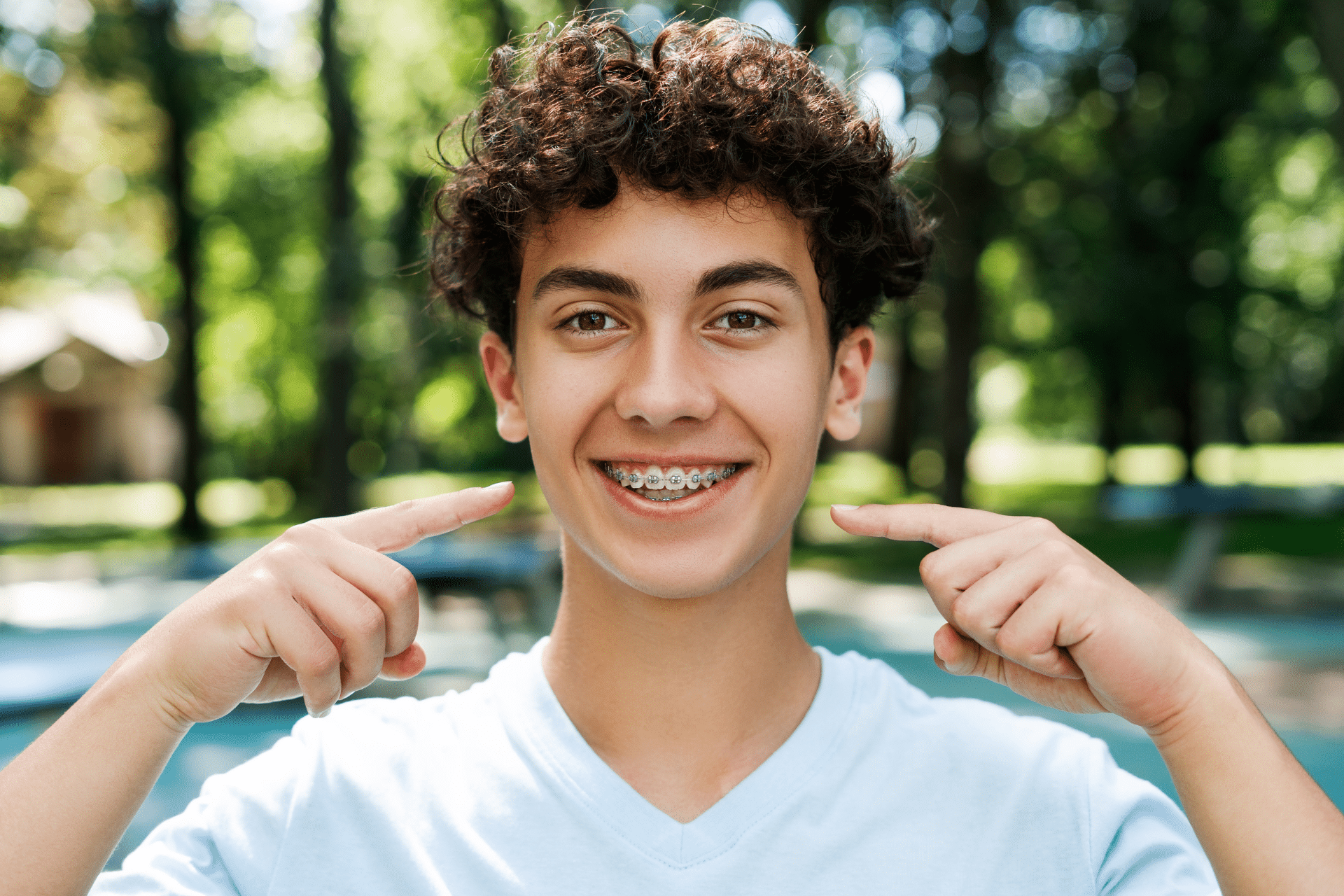 Teen smiling with braces while learning what can delay orthodontic treatment in Sugar Land TX