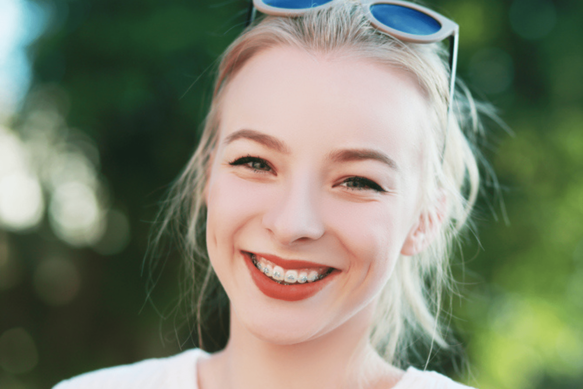 Smiling woman wearing metal braces with sunglasses resting on her head