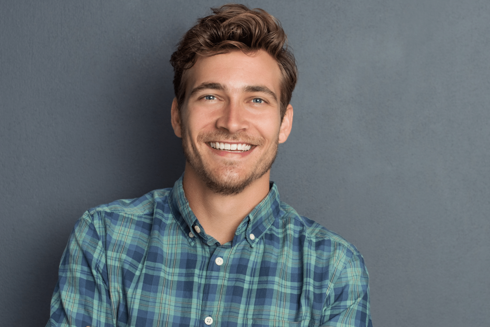 Smiling young man with light brown hair wearing a green and blue plaid shirt